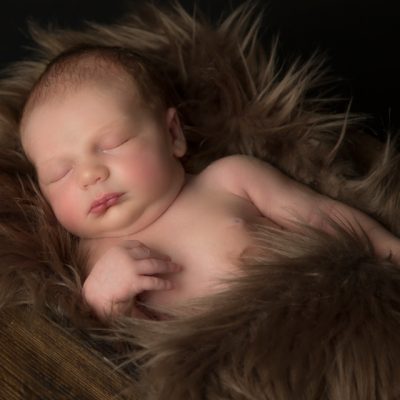 newborn baby asleep on brown faux fur