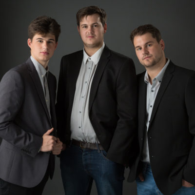 Three male siblings in dark suits