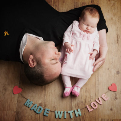 Dad lay on floor with baby cradled in his arm