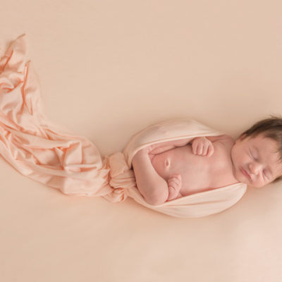 Newborn baby wrapped in peach fabric