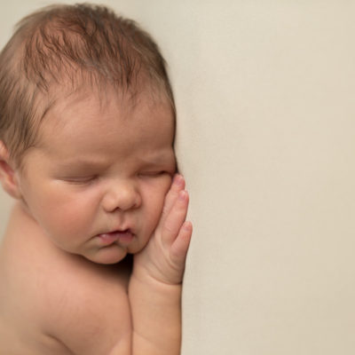 Newborn baby hand under cheek