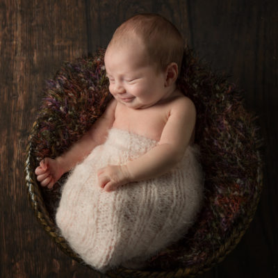 Newborn baby smiling in a basket