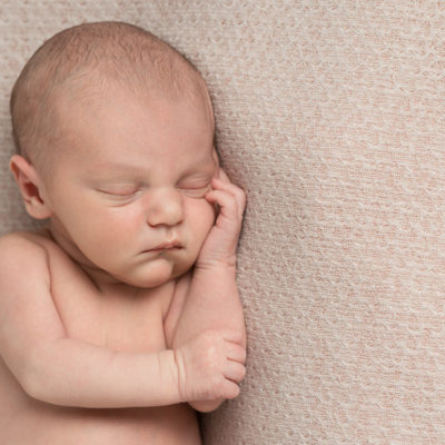 Newborn baby leaning on one arm