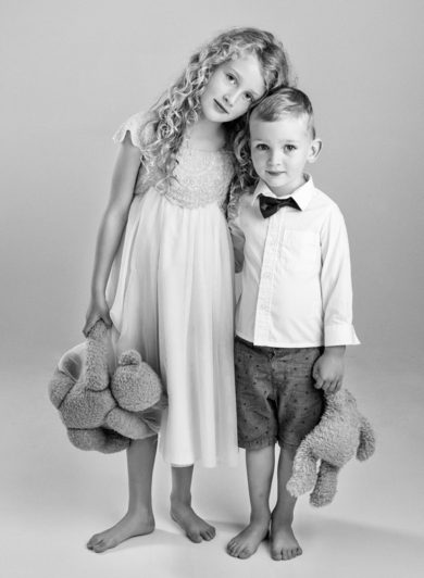 Young siblings hugging holding teddies